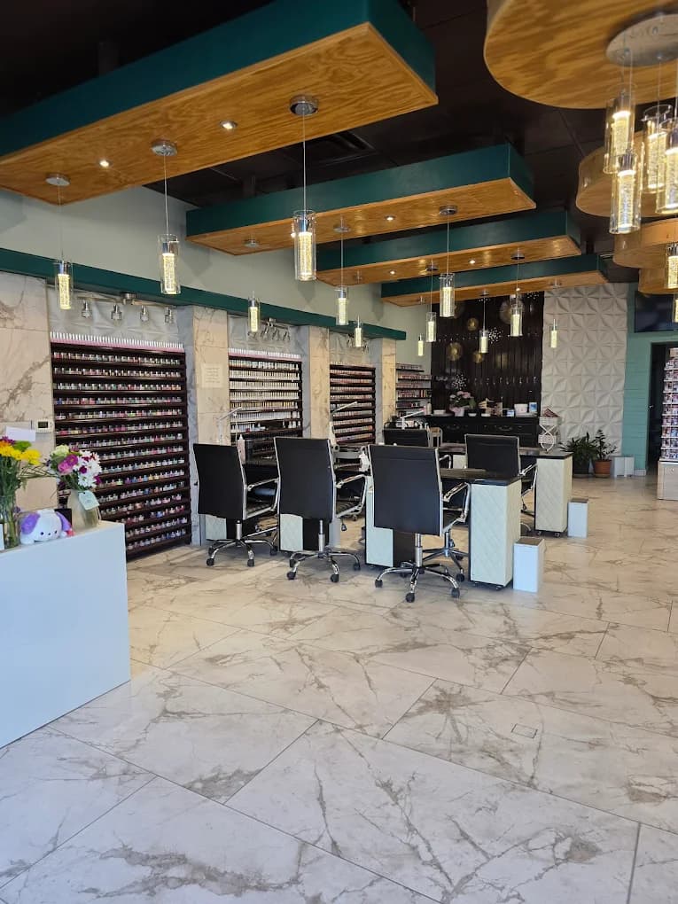 Interior of Royal Enchanted Nails and Spa — marble floors, polish wall, and manicure stations beneath warm pendant lighting